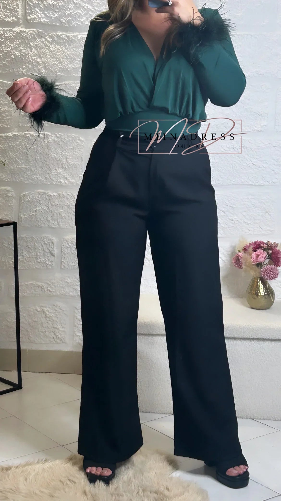 Femme portant un pantalon noir large et un haut vert manches longues à plumes, look chic moderne