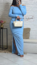Robe longue bleu clair à épaules dénudées, fendue, femme tenant un sac à main rayé