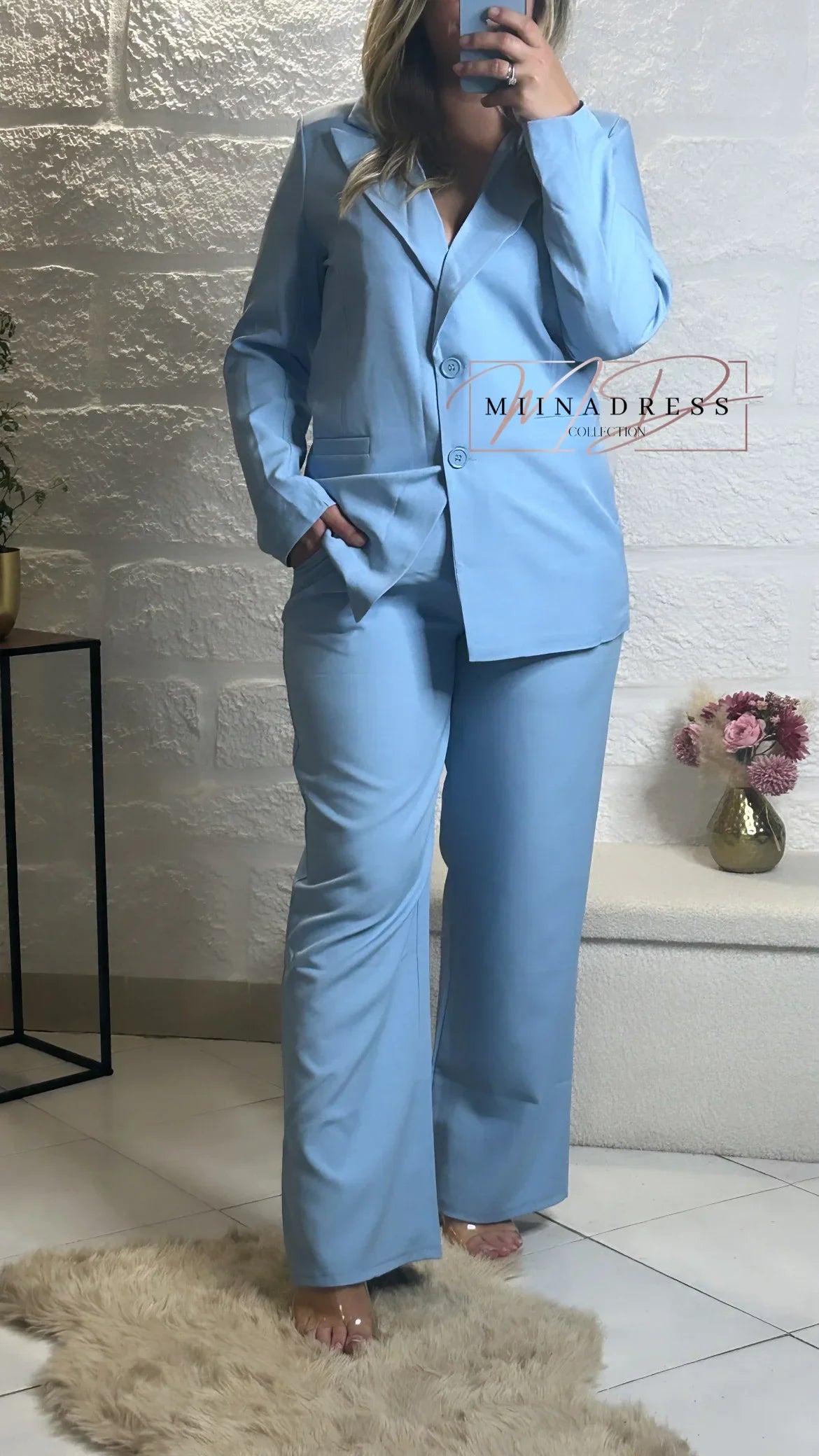 Femme portant un tailleur pantalon bleu clair tendance, ambiance chic et moderne intérieur.