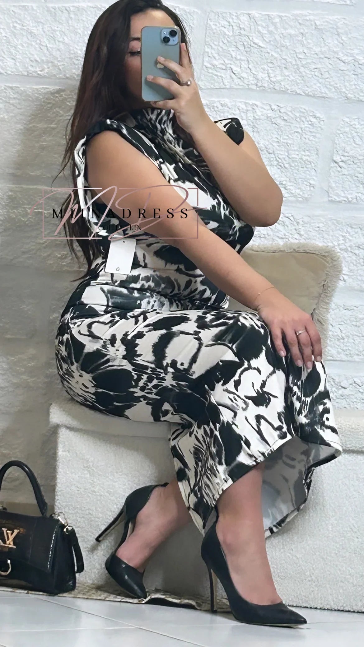 Femme en robe mi-longue imprimé noir et blanc, talons noirs, sac à main chic au sol