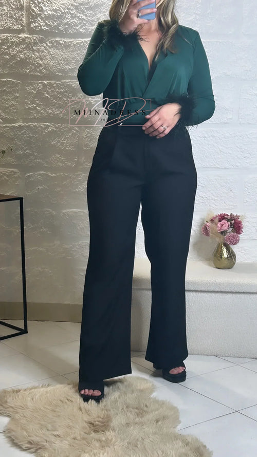 Femme portant un haut vert à plumes et un pantalon noir élégant, look chic et moderne