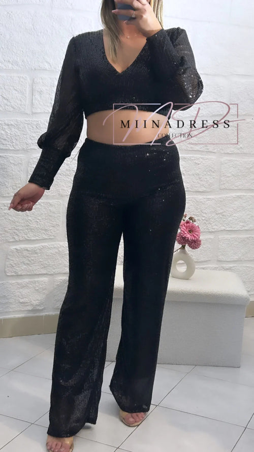 Femme portant un ensemble noir pailleté, crop top manches longues et pantalon large, look chic