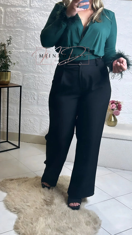 Femme portant un top vert à manches plumes et pantalon noir chic, look élégant moderne