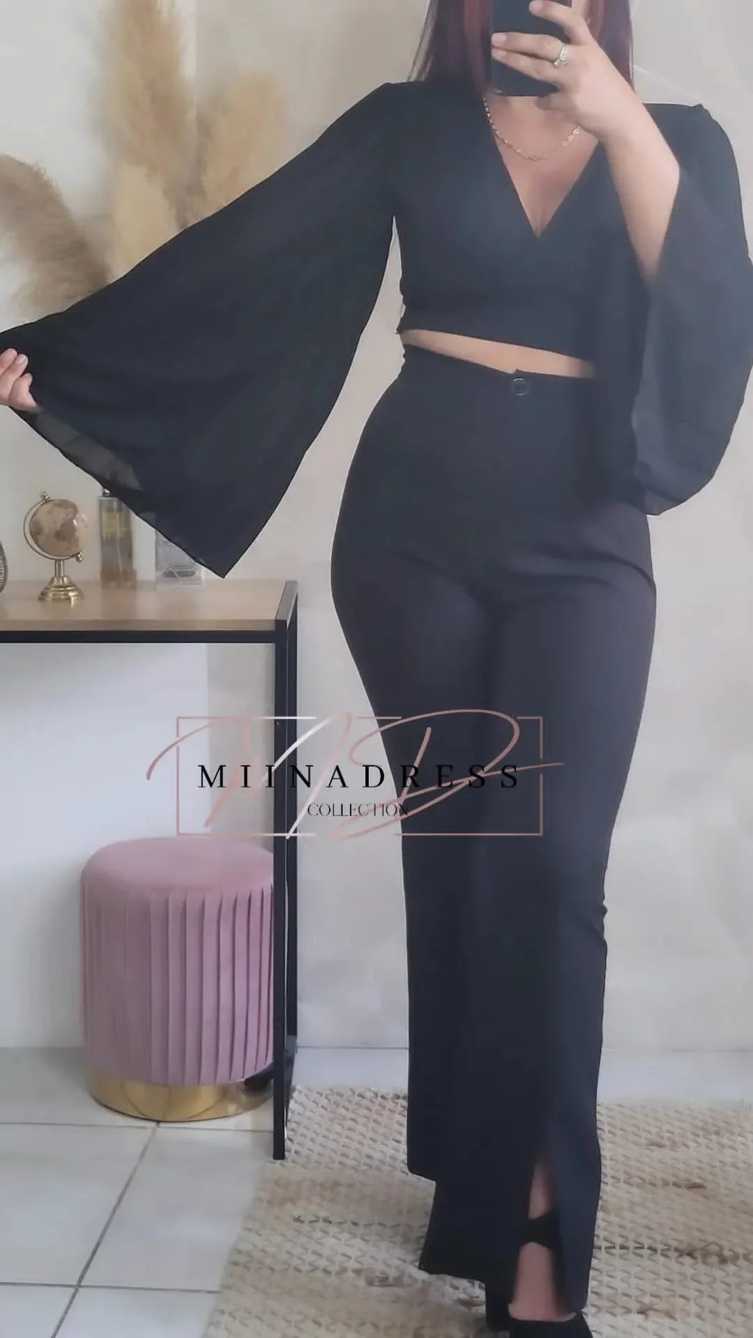Femme portant un ensemble noir élégant avec haut à manches larges et pantalon taille haute.