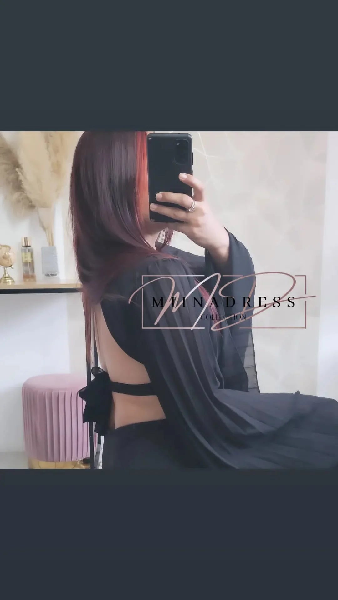 Femme portant une robe noire dos nu élégante, assise dans un intérieur moderne.